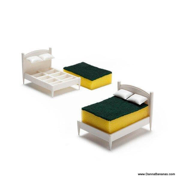 Introducing the Clean Dreams Kitchen Sponge Holder by Danna Bananas: These charming miniature beds, crafted from cleaning sponges, serve as unique kitchen sponge holders. Each holder comes with a yellow sponge mattress and a green scrub top, complete with small white frames and pillows that resemble real beds. Dishwasher safe for effortless maintenance, you can purchase them at www.dannabananas.com.