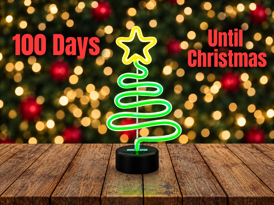 Glowing green neon Christmas tree light on a wooden table with text reading 100 Days Until Christmas