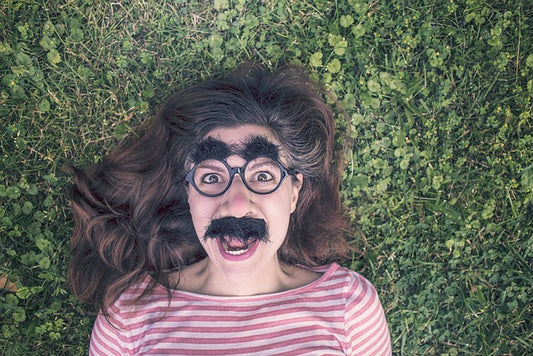 Woman lying on the grass with funny glasses on