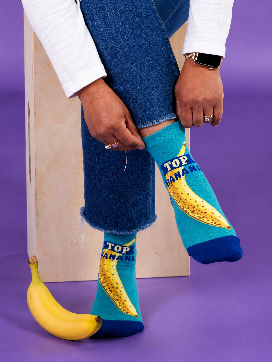 Top Banana women’s ankle socks with banana design and fresh banana on a purple background