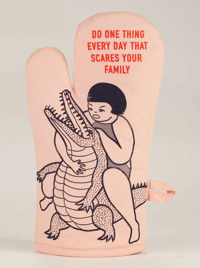 Humorous oven mitt with "Do One Thing Every Day That Scares Your Family" text and cartoon person wrestling an alligator.