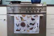Fowl Towel cotton tea towel hanging over a stainless steel oven door handle, featuring illustrated ducks, chickens, geese and a turkey.