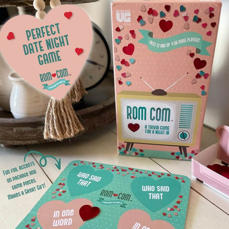 The "ROM COM - A Trivia Game for a Night In" by Danna Bananas comes in a box with pink and teal hearts, ideal for date nights. It features a retro TV design with the card question, "Who said that?" and is themed around romantic comedies, suitable for ages 17 and up.