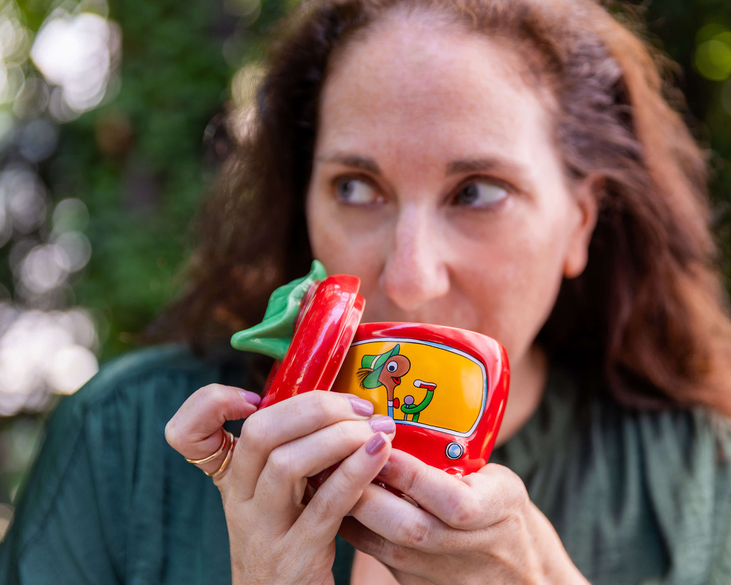 Woman drinking from the Richard Scarry Lowly Worm Applecar Mug, showing its removable lid and Lowly Worm at the wheel