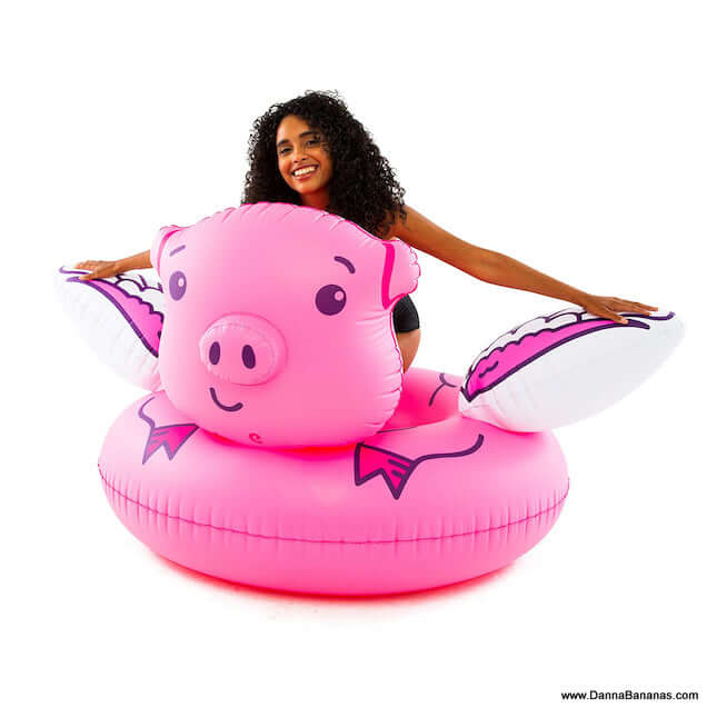 Woman sitting on Giant Flying Pig Pool Float. This float is five feet wide.