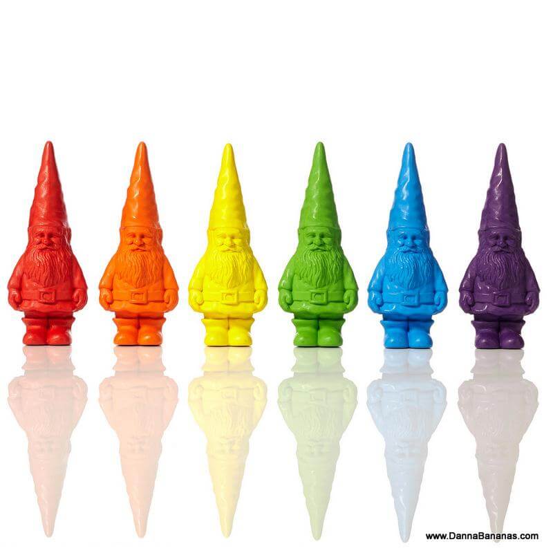 Six Bavarian Gnome Crayons from Danna Bananas are expertly crafted in vibrant shades of the rainbow: red, orange, yellow, green, blue, and purple. These non-toxic wax crayons feature gnomes with long beards and pointed hats, standing upright against a pure white background.
