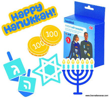 The vibrant Hanukkah-themed design features the text "Happy Hanukkah!" along with dreidels, gelt coins, a Star of David, and a menorah. The "Hanukkah Instant Ugly Sweater Kit" by Danna Bananas includes festive sweaters with embroidered patches and is modeled by two joyful individuals.