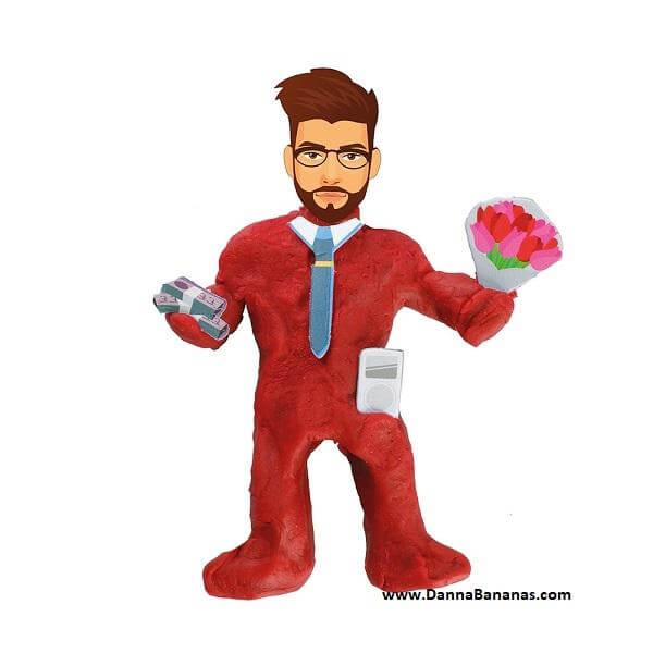 A cartoon character, perfectly capturing the essence of Danna Bananas' "Mould Your Own Dream Boyfriend," stands against a plain white background. He is dressed in a red suit, with glasses and a beard. In one hand, he holds a bouquet of flowers; in the other, a stack of money—embodying the ideal boyfriend from your imagination.