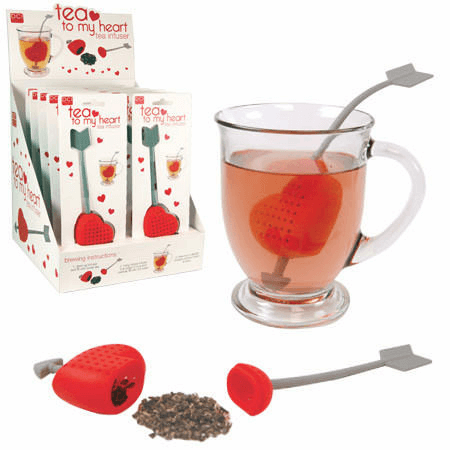 The "Tea to My Heart" Tea Infuser by Danna Bananas features a heart-shaped design on an arrow handle, nestled in a glass mug of tea. The packaging, ideal for Mother's Day gifting, highlights the product along with the phrase "tea to my heart." On display are loose tea leaves and the delightful infuser showcased separately on a surface.